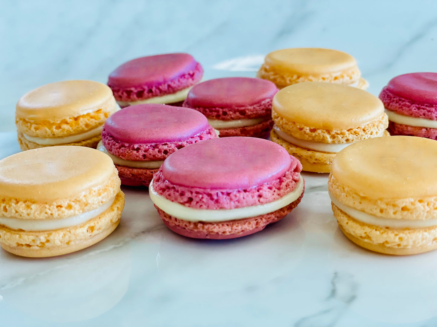 Raspberry and Orange Macarons in a row